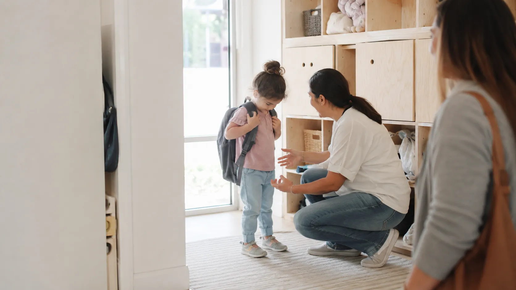 Educator welcoming a child at the classroom cubbies