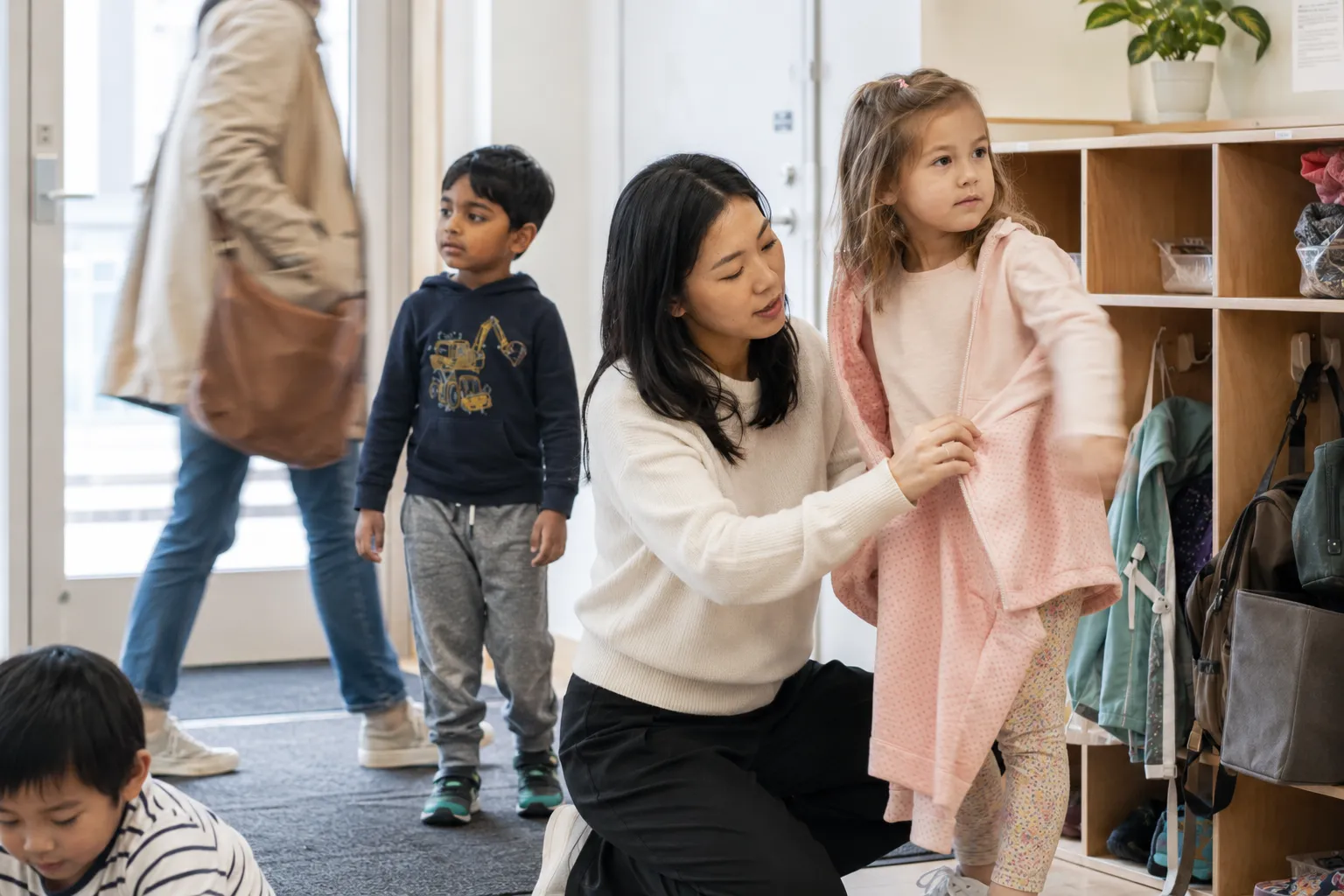 Educator helping a child with a jacket during arrival