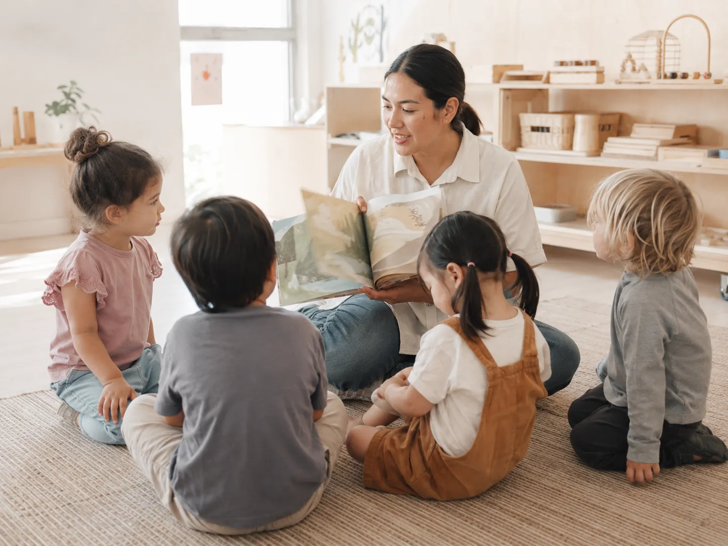 Educator reading a story with children seated in a bright classroom
